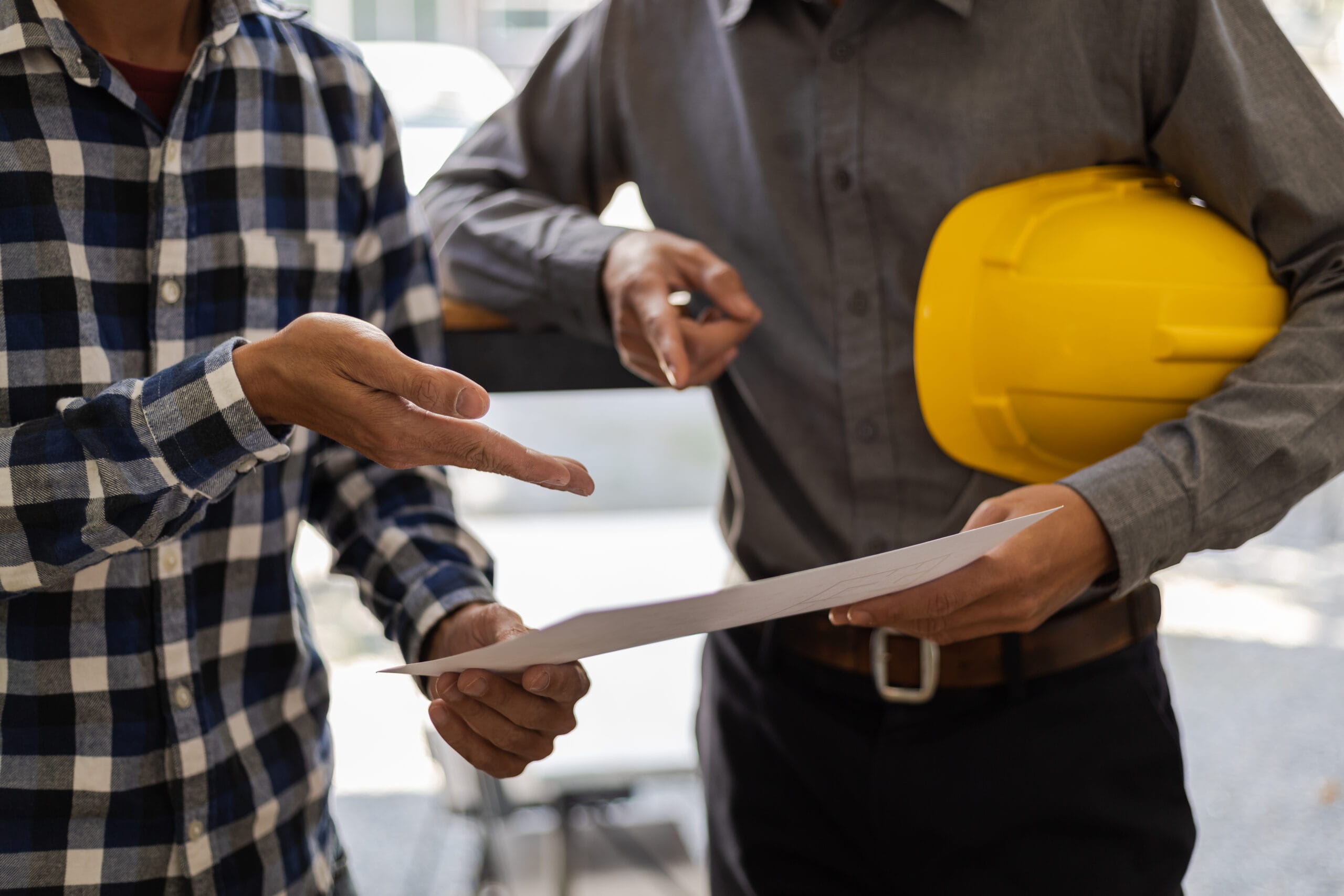 Mains d'un architecte et d'un ingénieur discutant d'un plan
