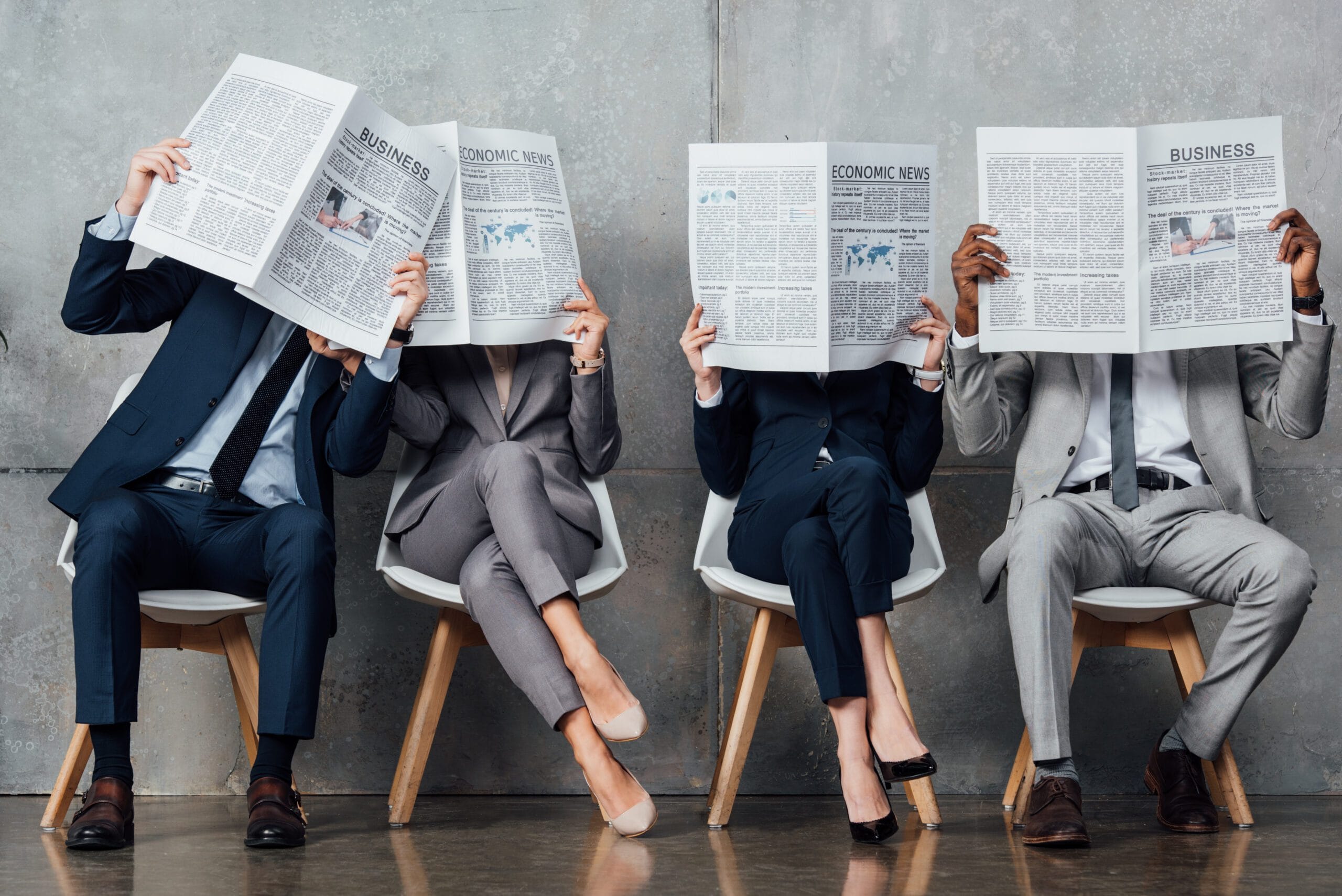 Personnes assises contre un mur lisant un journal