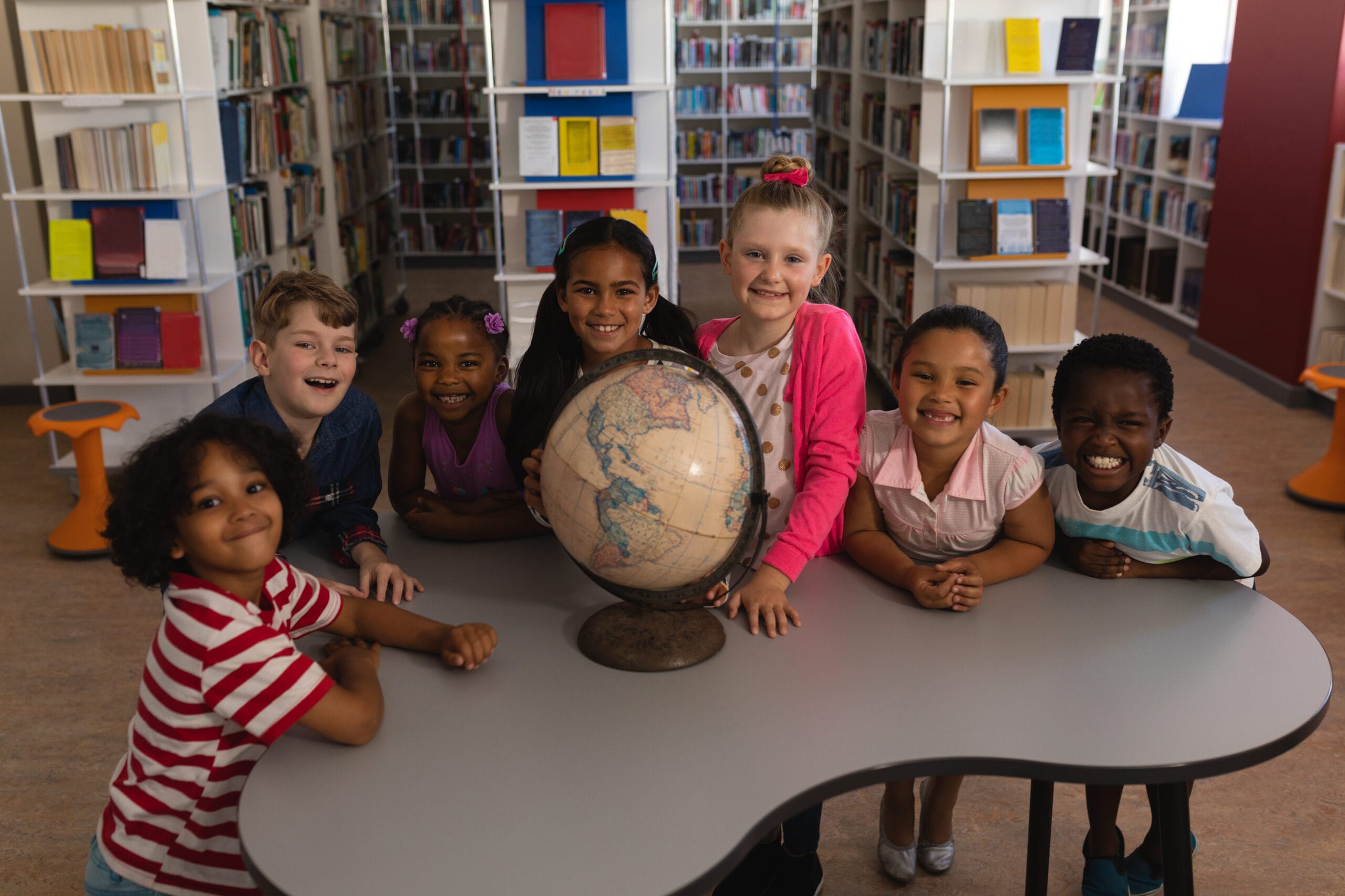 Enfants heureux autour d'un globe terrestre à la bibliothèque